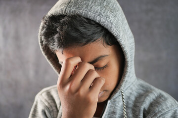 sad teenage boy covering his face sitting on sofa 