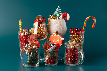 Glass cups with Christmas decor against dark green background