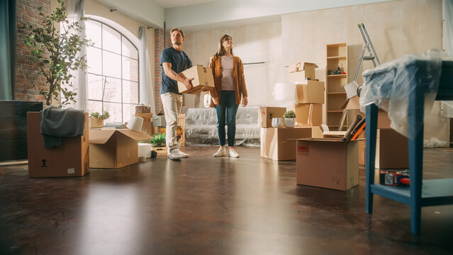 Family New Home Moving in: Happy and Excited Young Couple Enter Newly Purchased Apartment. Beautiful Family Happily Looking Around. Modern Home Ready for Decorations.