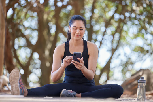 Fitness, relax and woman in park with phone on break after running, exercise and workout in nature. Sports, wellness and happy girl on smartphone for training blog, health mobile app and social media