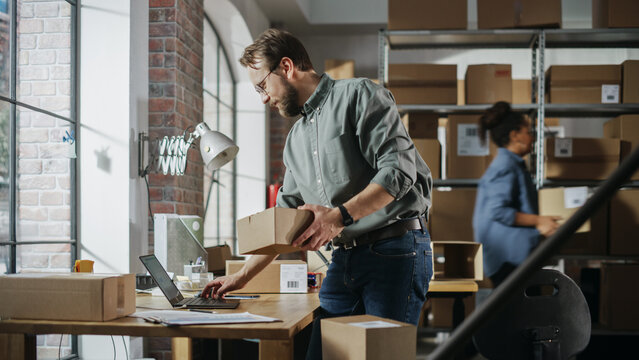 Busy Day At Warehouse. Multicultural Employees At Work In Retail Shop's Storeroom. Small Business Owners Working On Laptop, Preparing And Packing Parcels For Delivery.