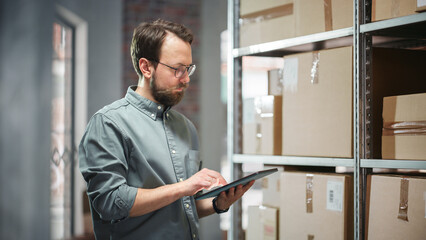 Portrait of a Successful Employee Checking Inventory, Writing in Tablet Computer. Stylish Man...