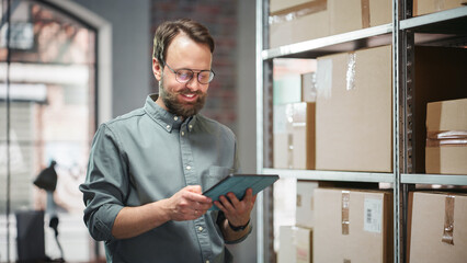 Portrait of a Happy Small Warehouse Employee Checking Inventory, Using Tablet. Handsome Man with...