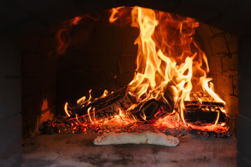 Italian food. Traditional calzone preparing in oven with open fire - Powered by Adobe