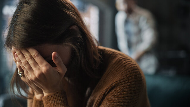 Portrait Of Crying Woman Covering Her Face With Hands, Being Harrased And Bullied By Violent Partner. Couple Arguing, Fighting, Domestic Abuse, Toxic Masculinity. Rack Focus With Boyfriend Screaming