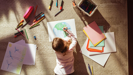 Top View: Little Girl Drawing Our Beautiful Green Planet Earth. Child Having Fun at Home on the...