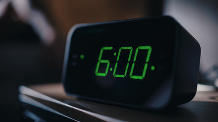 Person Wakes Up and Turns off Alarm Clock. Early Rising Productive Person Ready Start a Day with New Adventures. Close-up Focus on the Clock Showing Six A.M. Bedside Nightstand bedroom Apartment