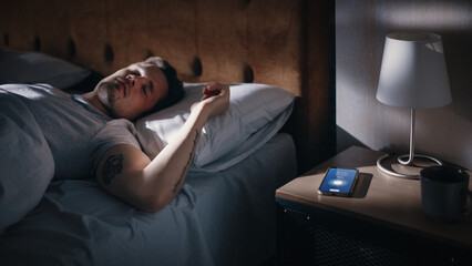 Caucasian Man Sleeps through Smartphone Alarm Clock Showing Eight in the Morning. Tired Person...