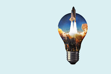 Creative light bulb with a night city, smoke and a rocket taking off. Creative idea and technology....