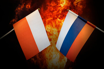 Flags of Russia and Poland against background of a fiery explosion. The concept of enmity and war...