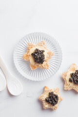 Black caviar appetizers bread star on a white background top view