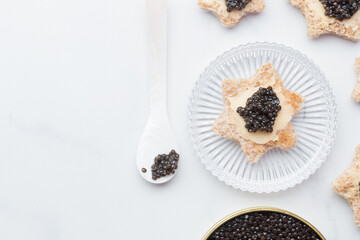 Black caviar appetizers bread star on a white background top view