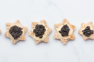Black caviar appetizers bread star on a white background top view