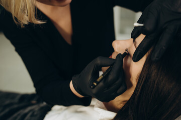 Master glues eyelashes to pink lash roller. Close-up of beauty model's face during lash lift...