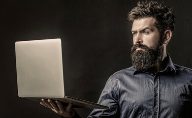 Holding a computer in his hands isolated on black background. Businessman using his laptop, pc