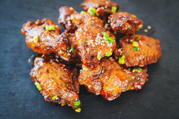 fried chicken with garlic and sesame in caramel on a black tray.