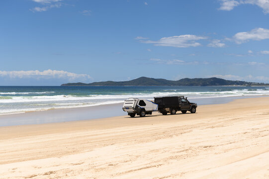 Off road vehicle driving on sandy beach with trailer