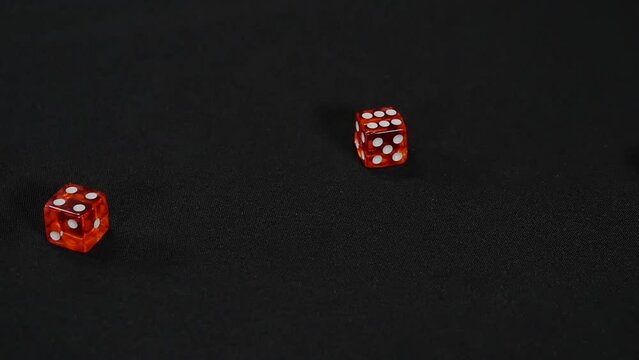 Rolling two red dice on black background, Slow motion