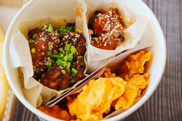 caramelized chicken with sesame and garlic, meat strips in paper bucket 