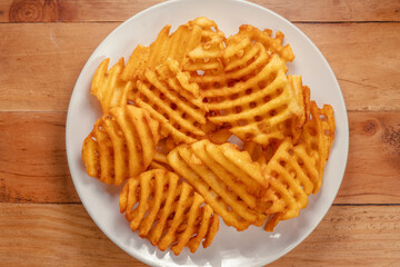Fried Wafer Potato in white plate on wooden background, Fried wafer potato on wooden background.