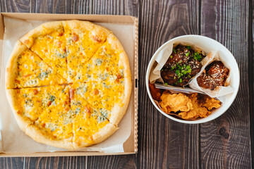 cheese pizza and caramelized chicken, meat strips in paper bucket 