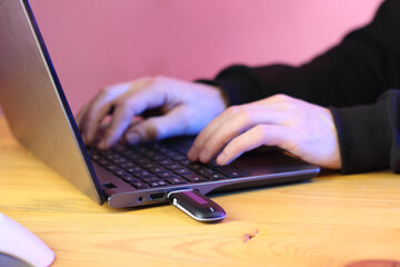 black gsm modem in a laptop against the background of a person typing on a keyboard