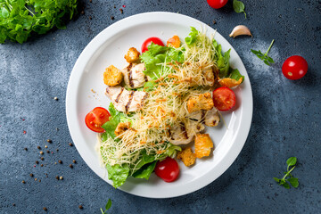 Salad caesar with chicken on white plate top view
