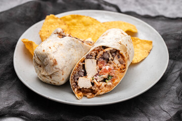 Mexican beef burrito on small plate with chips nachos