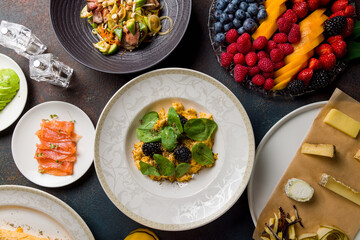 scramble with spinach and truffle, avocado, salmon, omelete, berries plate, cheese plate, asian salad with beef on stone table top view