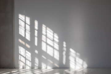 Fragment of room with empty white wall where sunlight shining through a window - concept of sunbeams to overlay a photo