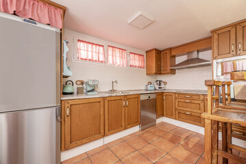 Kitchen furnished with rustic-style wooden furniture and light-colored countertops with stainless steel appliances