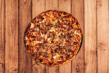 A great family barbecue pizza seen from the top on a warped wooden table