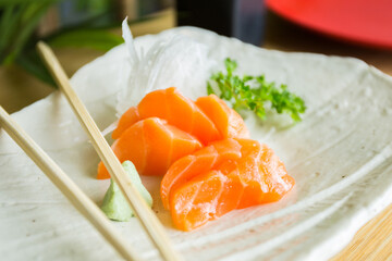 Salmon sashimi. Sashimi is a Japanese dish that consists mainly of raw seafood or fish, finely sliced, although not as finely as a carpaccio. A sauce and a simple dressing are served with them.
