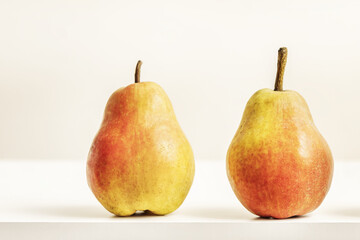 Two delicious ripe pears on a white surface