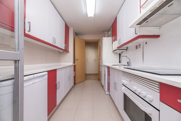 kitchen of a single-family home with red and white wood furniture with matching appliances, stoneware floors and oak carpentry on the doors