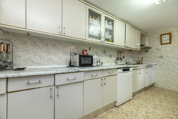 Wall of an old kitchen with white furniture and stoneware on floors and walls