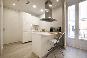 Open kitchen in a vacation rental studio with white furniture and balconies with white wooden windows
