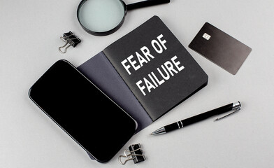 FEAR OF FAILURE text written on black notebook with smartphone, magnifier and credit card