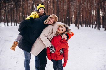 Photo of cheerful family - mommy, daddy, son and daughter piggyback happy positive smile. winter trip , outdoors