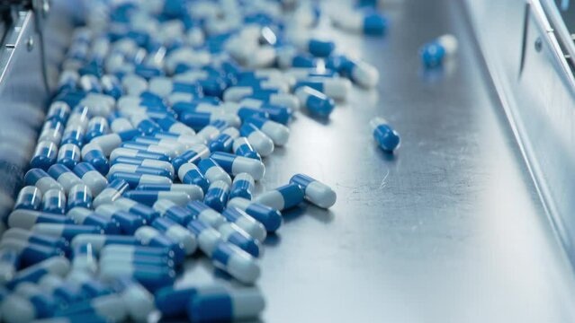 Capsules are Moving towards Camera on Conveyor at Modern Pharmaceutical Factory. Tablet and Capsule Manufacturing Process. Close-up Shot of Medicinal Drug Production Line.