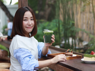 Smiling woman drinking matcha green tea latte in the morning