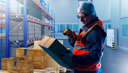 Warehouse worker. Man storekeeper with device for revision. Gray-haired man works in warehouse....