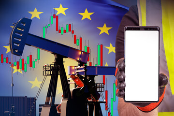 Oil derrick. Workers hand with phone. Oil production in European Union. Oil pump with flag of Europe. Phone with white screen. Copy Space in smartphone. Fuel industry European Union. Phone template