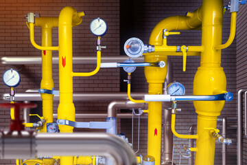 Yellow pipes in basement. Gas industry. Pipes with pressure meters. Gas pipeline near brick wall....