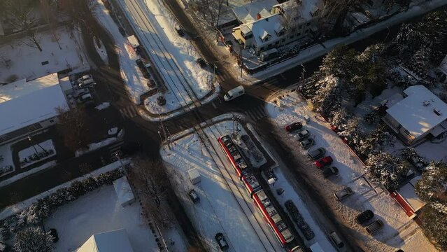 The car in the ground standing in front of the railway crossing. Train leaving the station. Winter and cold day. Aerial view from drone.