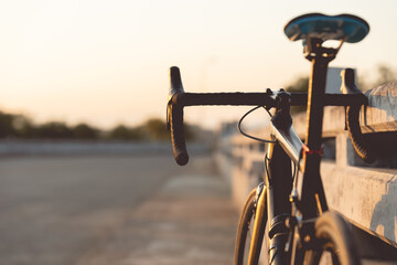 Road bike parked on a beautiful road sunset, warm light with copy space.