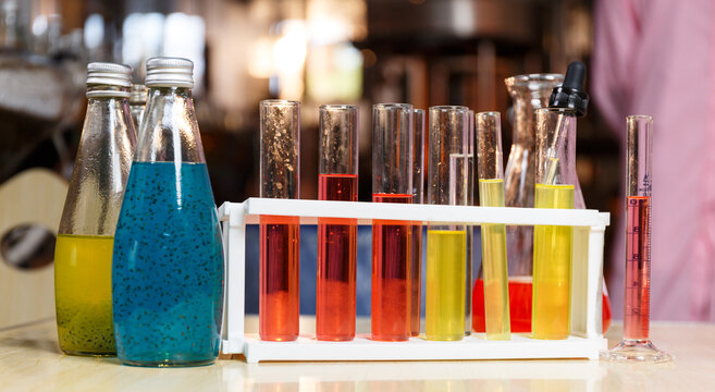 Juice in bottles and test tubes to sample the finished product on the table in a beverage factory.