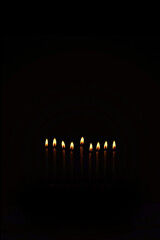 Religious image of Jewish holiday Hanukkah with candles of menorah on black background