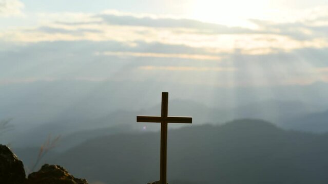 Christian cross in the glow of the sun, mountain landscape above the clouds