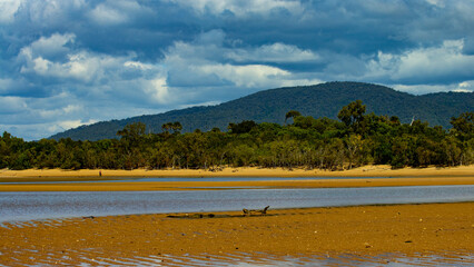 Walking tourist with camera on Balgach beach in Queensland, Australia. Small idyllic tropical beach near Townsville. 